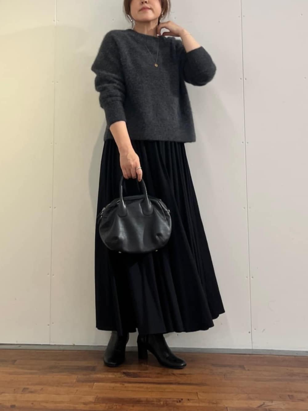 ブラック系のスカート、グレー系のニット/セーターを着用したレディースの秋コーディネートの3枚目の写真