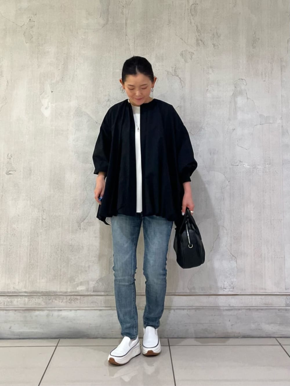 ホワイト系のスニーカー、ブルー系のデニムパンツ、ブラック系のボストンバッグを着用したレディースの冬コーディネートの2枚目の写真