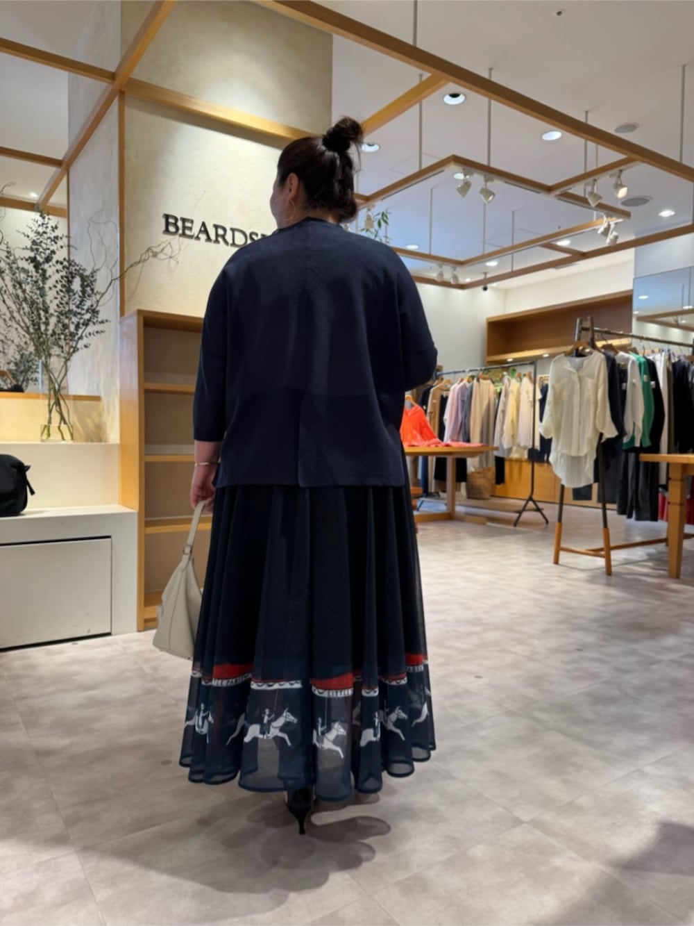 ホワイト系のトートバッグ、ブルー系のカーディガン/ボレロ、ブルー系のスカートを着用したレディースの春コーディネートの4枚目の写真