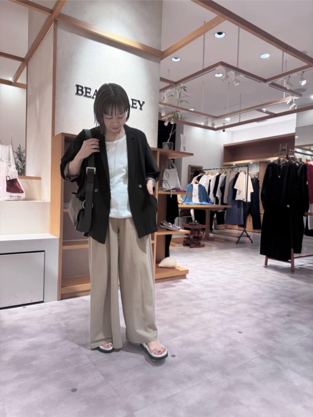 ブラック系のテーラードジャケット、ベージュ系のその他パンツ、ホワイト系のサンダルを着用したレディースの春コーディネートの6枚目の写真
