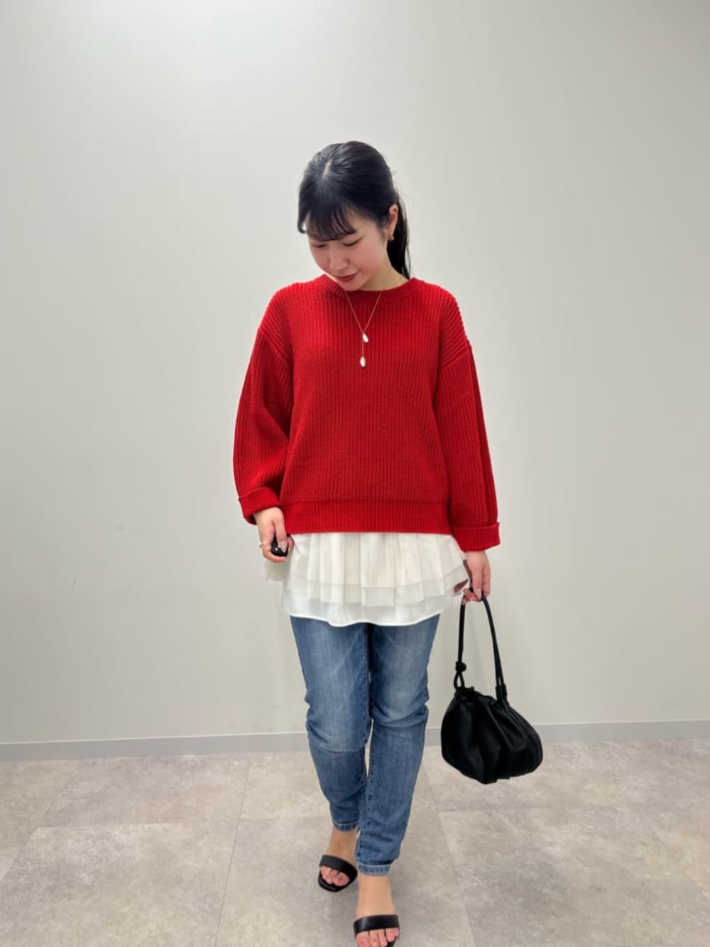 ブルー系のデニムパンツ、ホワイト系のタンクトップ、レッド系のニット/セーターを着用したレディースの冬コーディネートの5枚目の写真