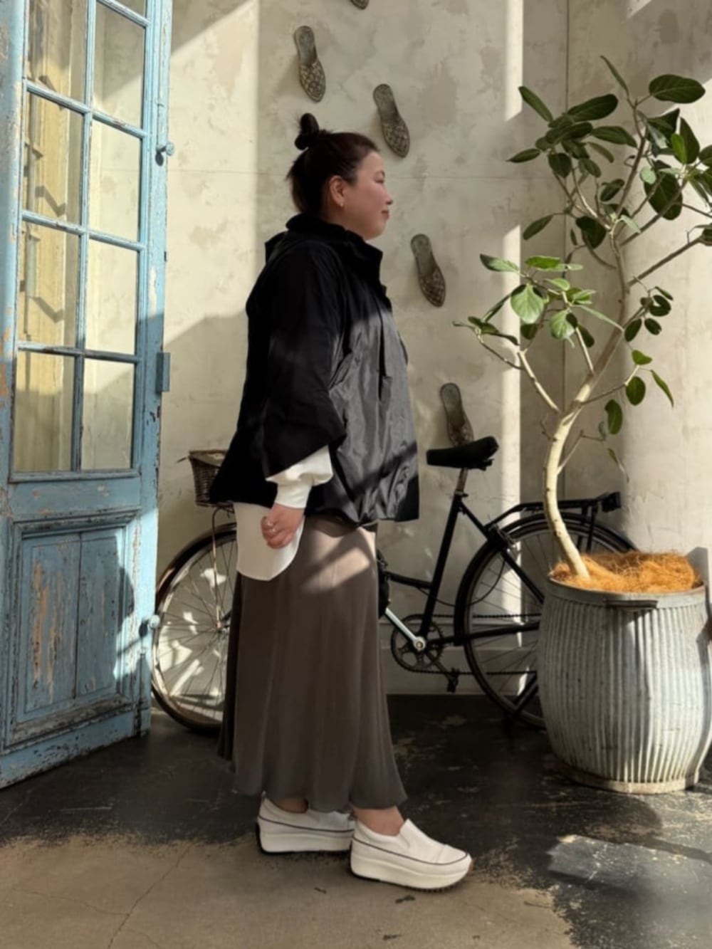 グリーン系のスカート、ブラック系のボストンバッグ、ホワイト系のシャツ/ブラウスを着用したレディースの冬コーディネートの2枚目の写真