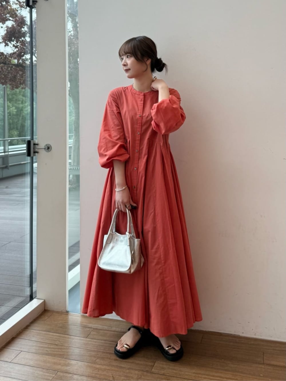 シルバー系のトートバッグ、オレンジ系のワンピース、ブラック系のサンダルを着用したレディースの冬コーディネートの2枚目の写真