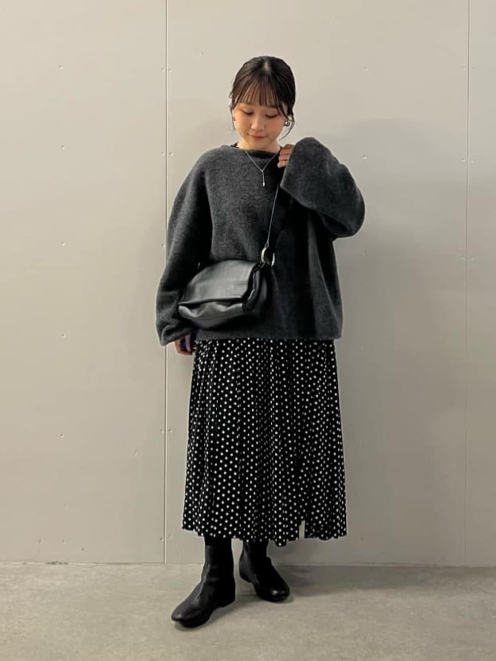 ブラック系のワンピース、ブラック系のブーツ、グレー系のニット/セーターを着用したレディースの冬コーディネートの3枚目の写真