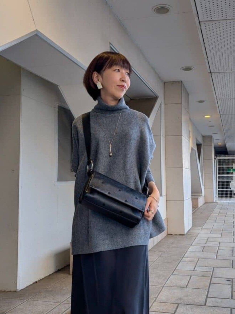 ブラック系のスカート、グレー系のニット/セーター、ブラック系のショルダーバッグを着用したレディースの冬コーディネートの6枚目の写真