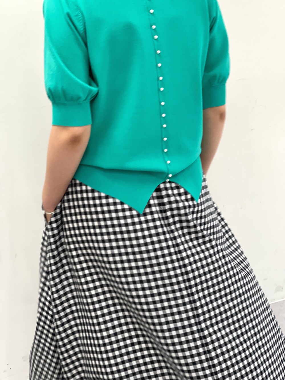 グリーン系のニット/セーター、ホワイト系のスカートを着用したレディースの夏コーディネートの3枚目の写真