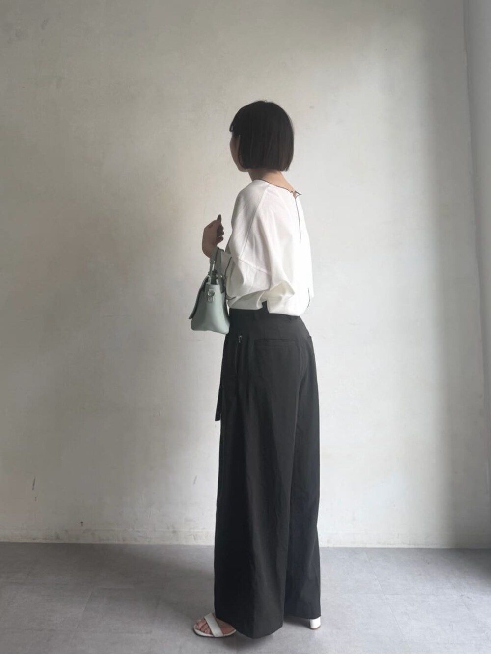 グリーン系のハンドバッグ、グレー系のその他パンツ、ホワイト系のTシャツ/カットソーを着用したレディースの冬コーディネートの3枚目の写真