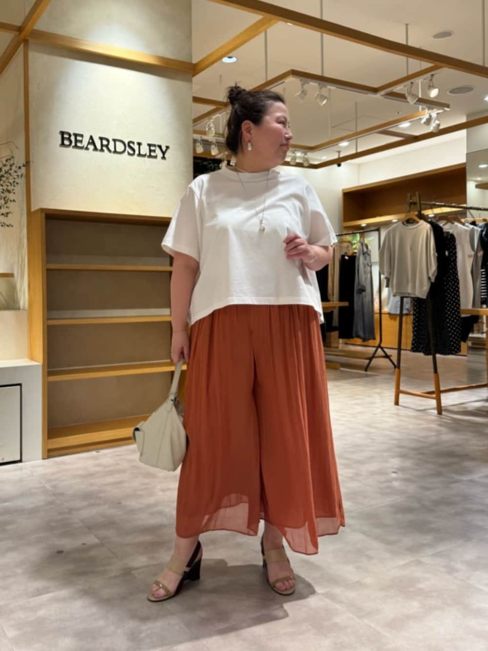 ホワイト系のトートバッグ、オレンジ系のその他パンツ、ホワイト系のTシャツ/カットソーを着用したレディースの春コーディネートの5枚目の写真