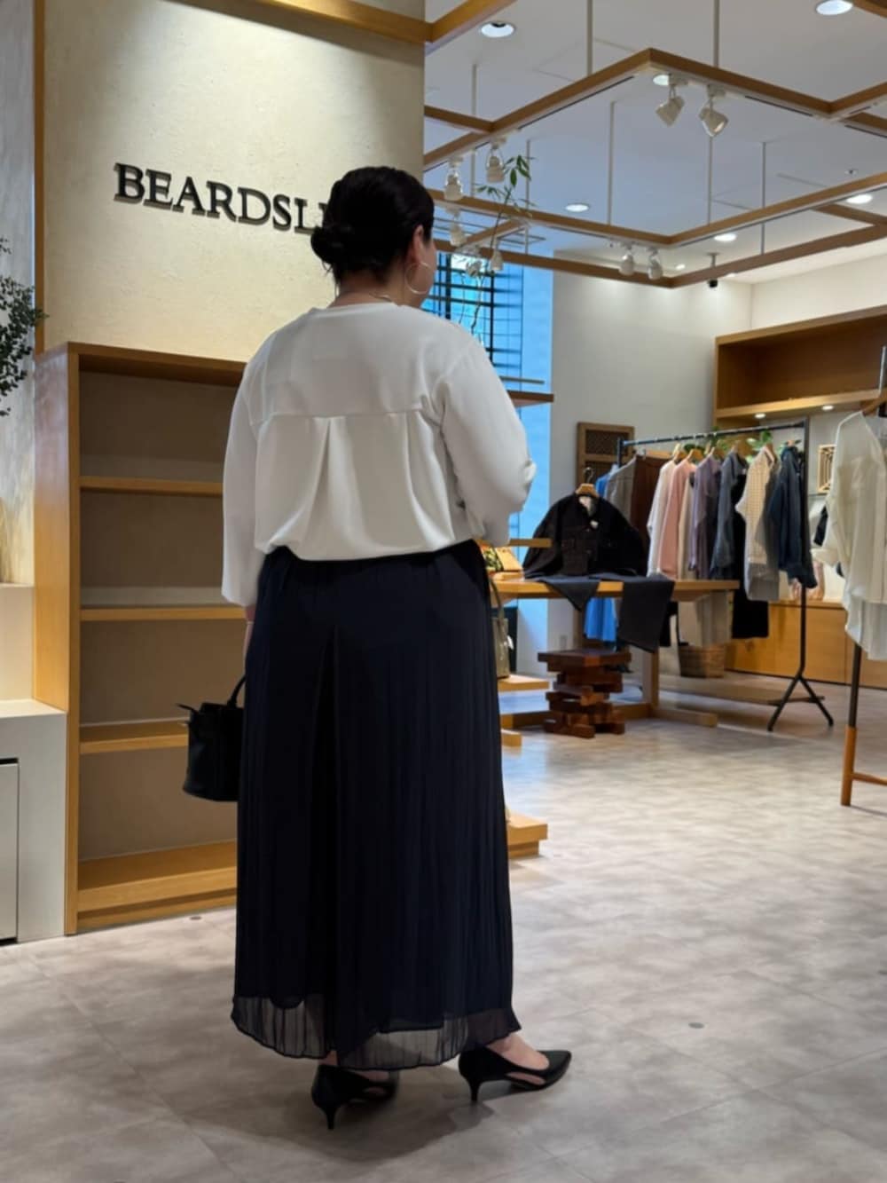 ブラック系のハンドバッグ、ホワイト系のシャツ/ブラウス、ブラック系のその他パンツを着用したレディースの春コーディネートの3枚目の写真