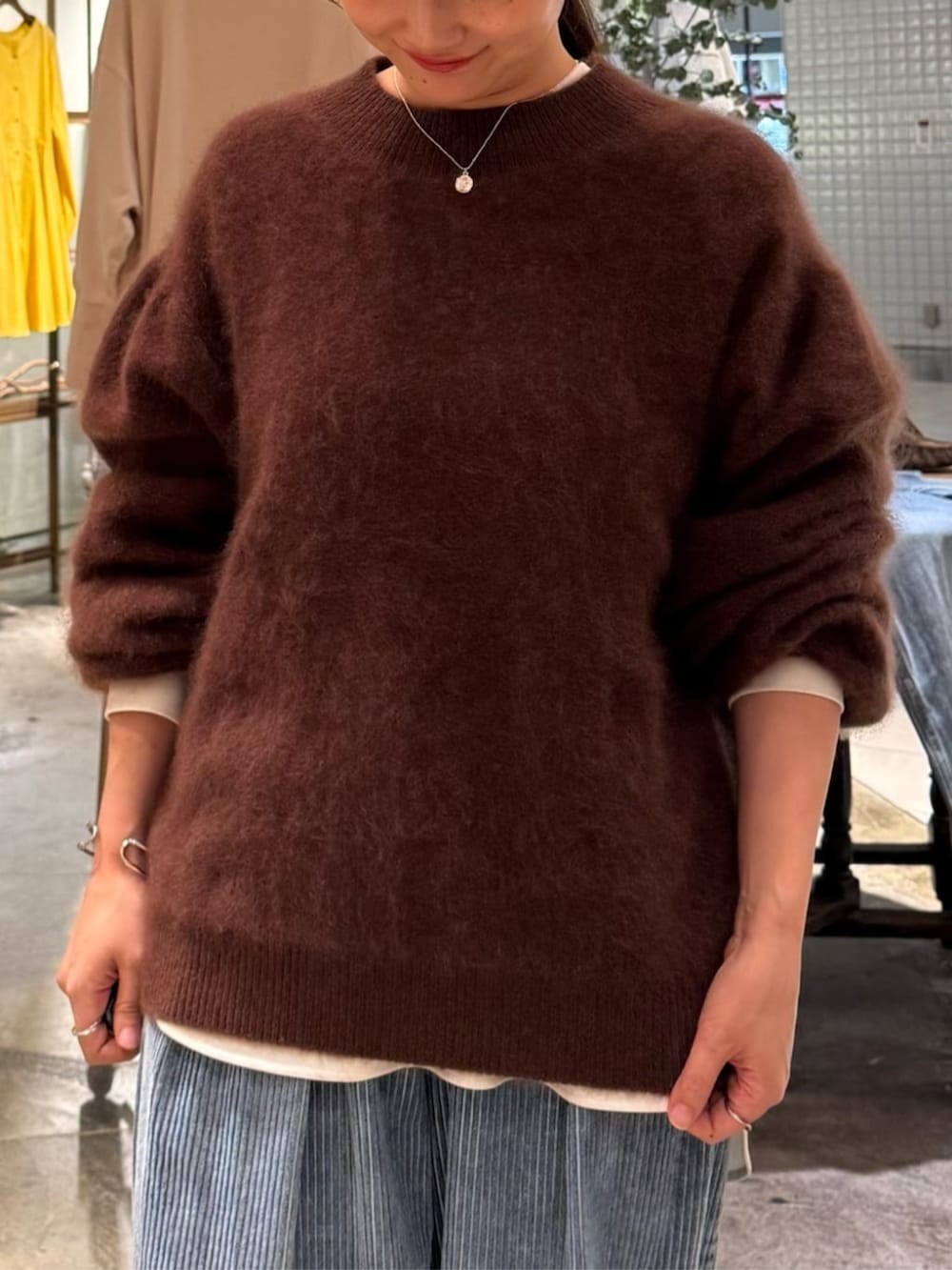 ブラック系のショルダーバッグ、ブラウン系のニット/セーター、ブルー系のその他パンツを着用したレディースの秋コーディネートの6枚目の写真