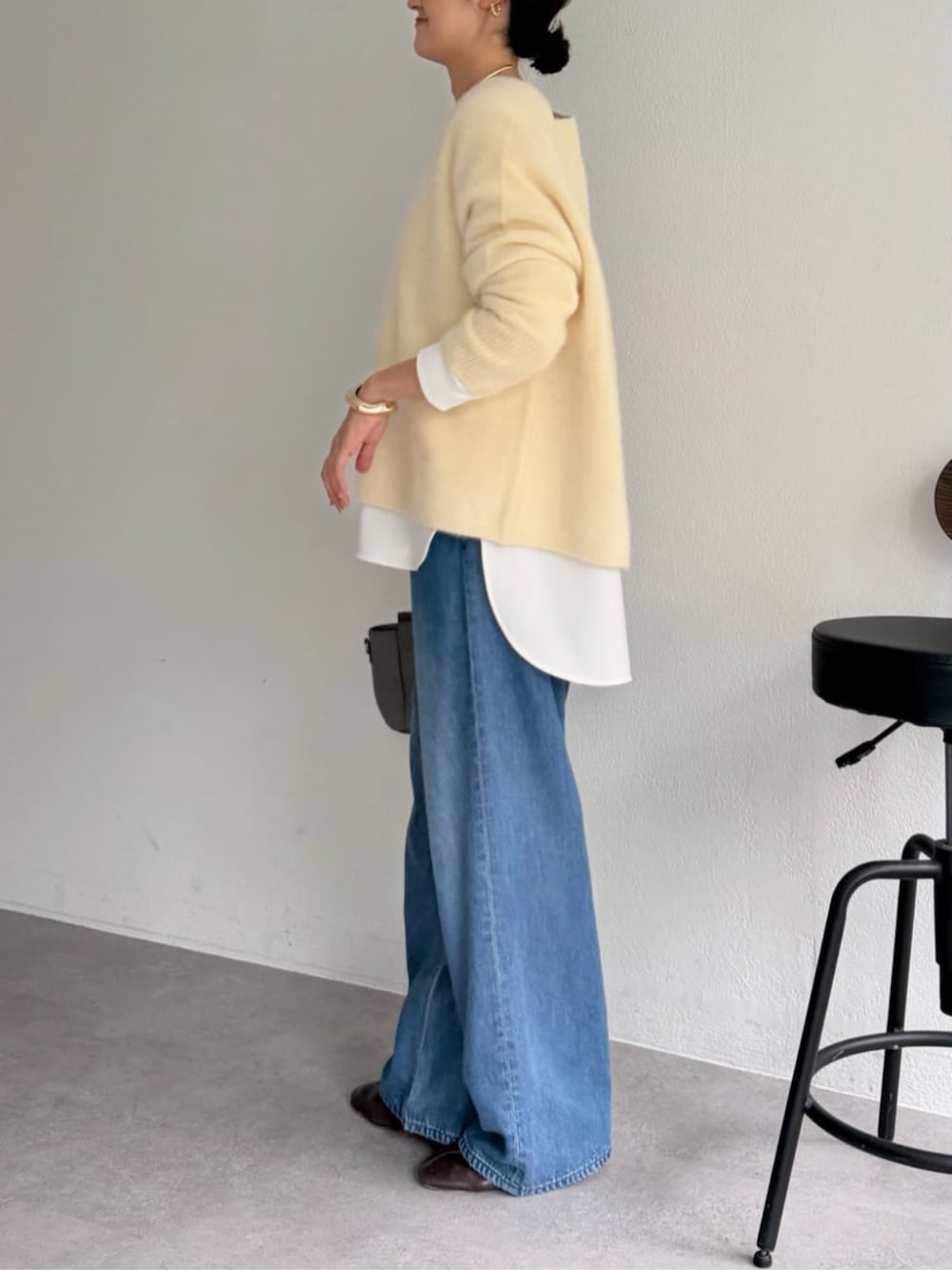 グレー系のハンドバッグ、ホワイト系のシャツ/ブラウス、イエロー系のニット/セーターを着用したレディースの秋コーディネートの7枚目の写真