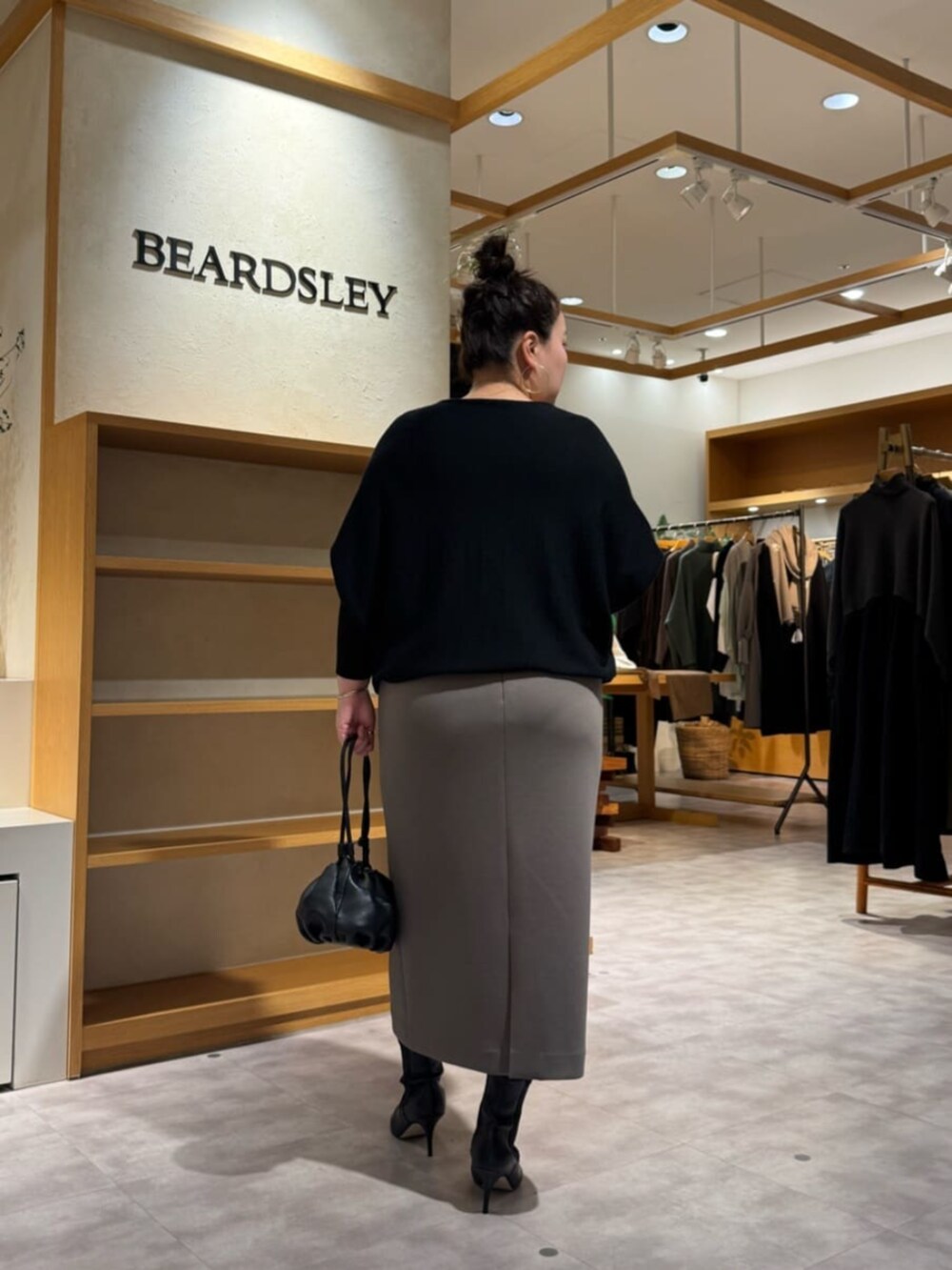 ブラック系のニット/セーター、ブラック系のブーツ、ブラウン系のスカートを着用したレディースの冬コーディネートの6枚目の写真