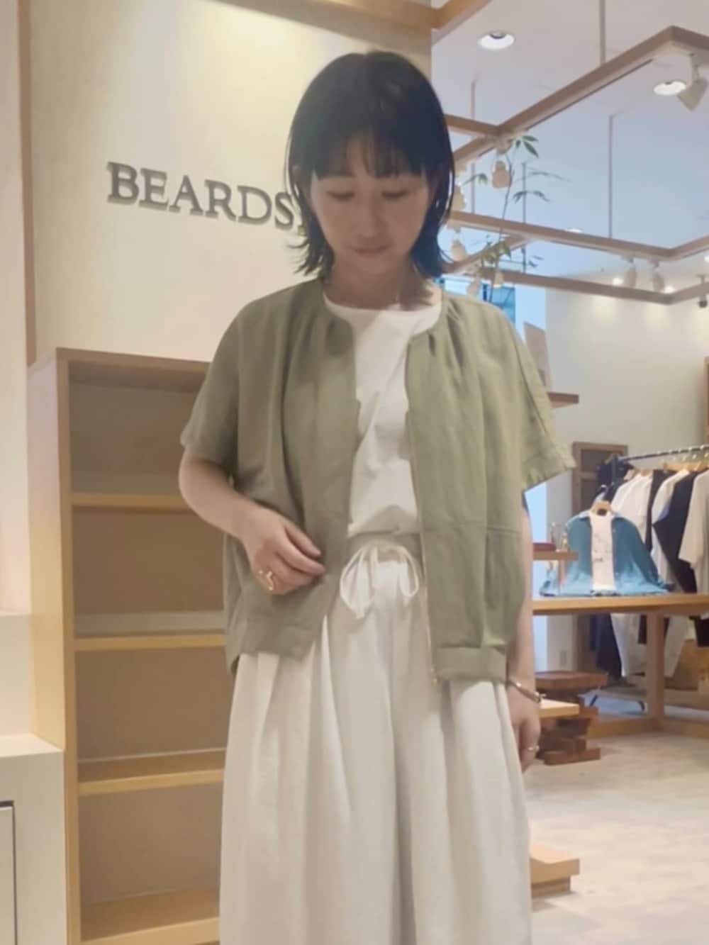 ブラック系のショルダーバッグ、ホワイト系のその他パンツ、グリーン系のベストを着用したレディースの春コーディネートの6枚目の写真