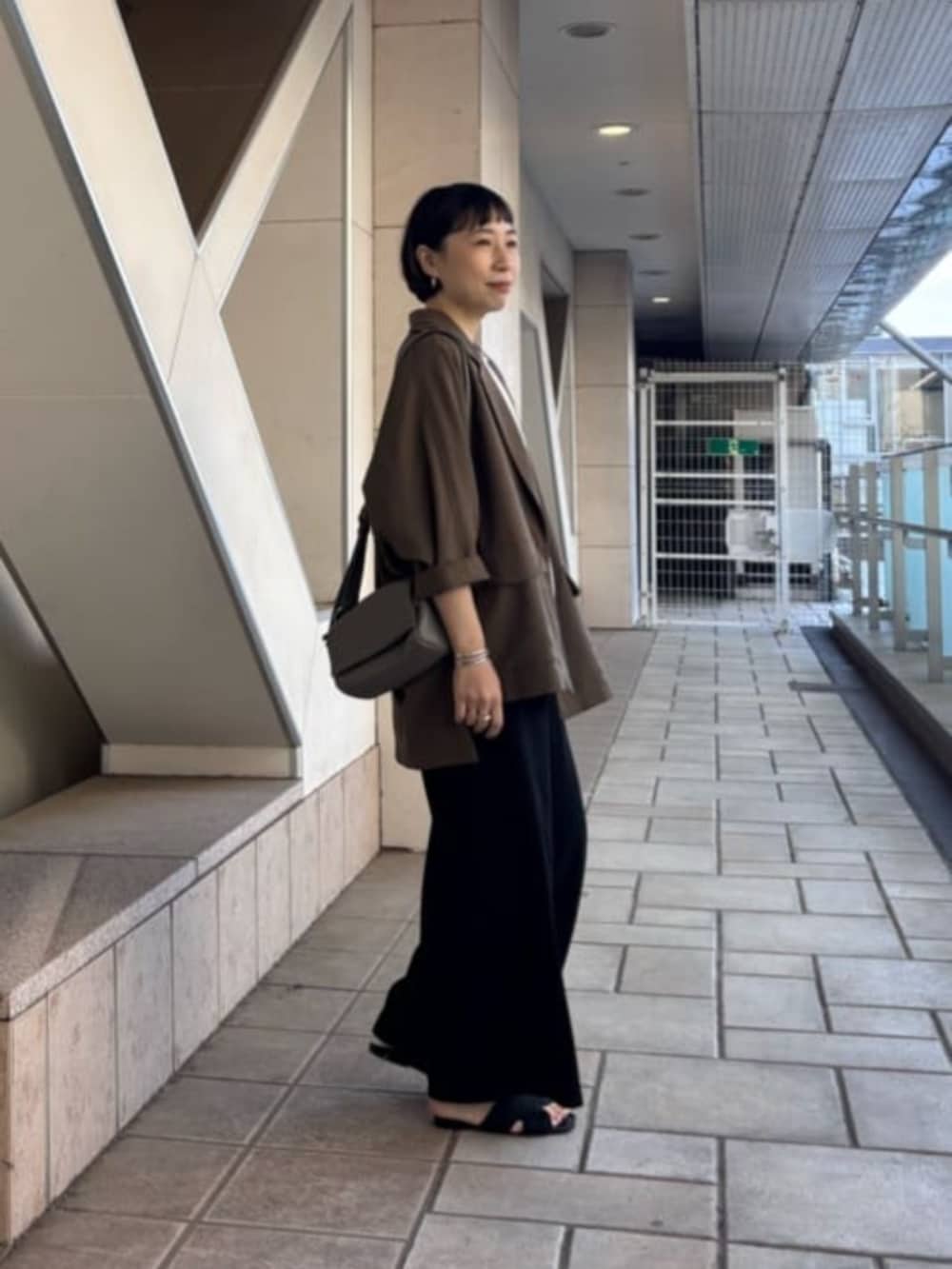 ブラック系のその他パンツ、ブラウン系のテーラードジャケット、ホワイト系のTシャツ/カットソーを着用したレディースの春コーディネートの3枚目の写真