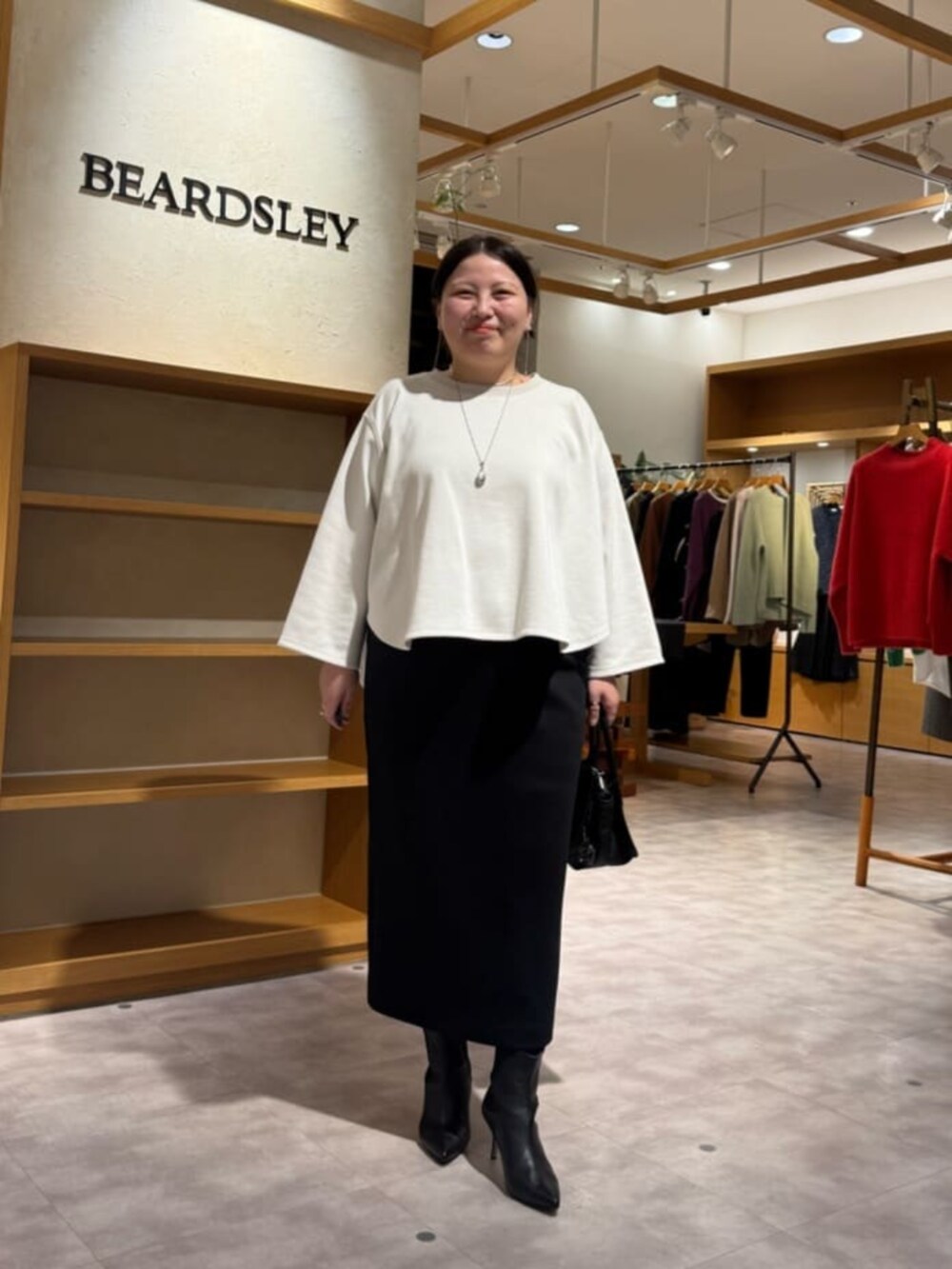 ブラック系のブーツ、ブラック系のスカート、ホワイト系のTシャツ/カットソーを着用したレディースの冬コーディネートの4枚目の写真