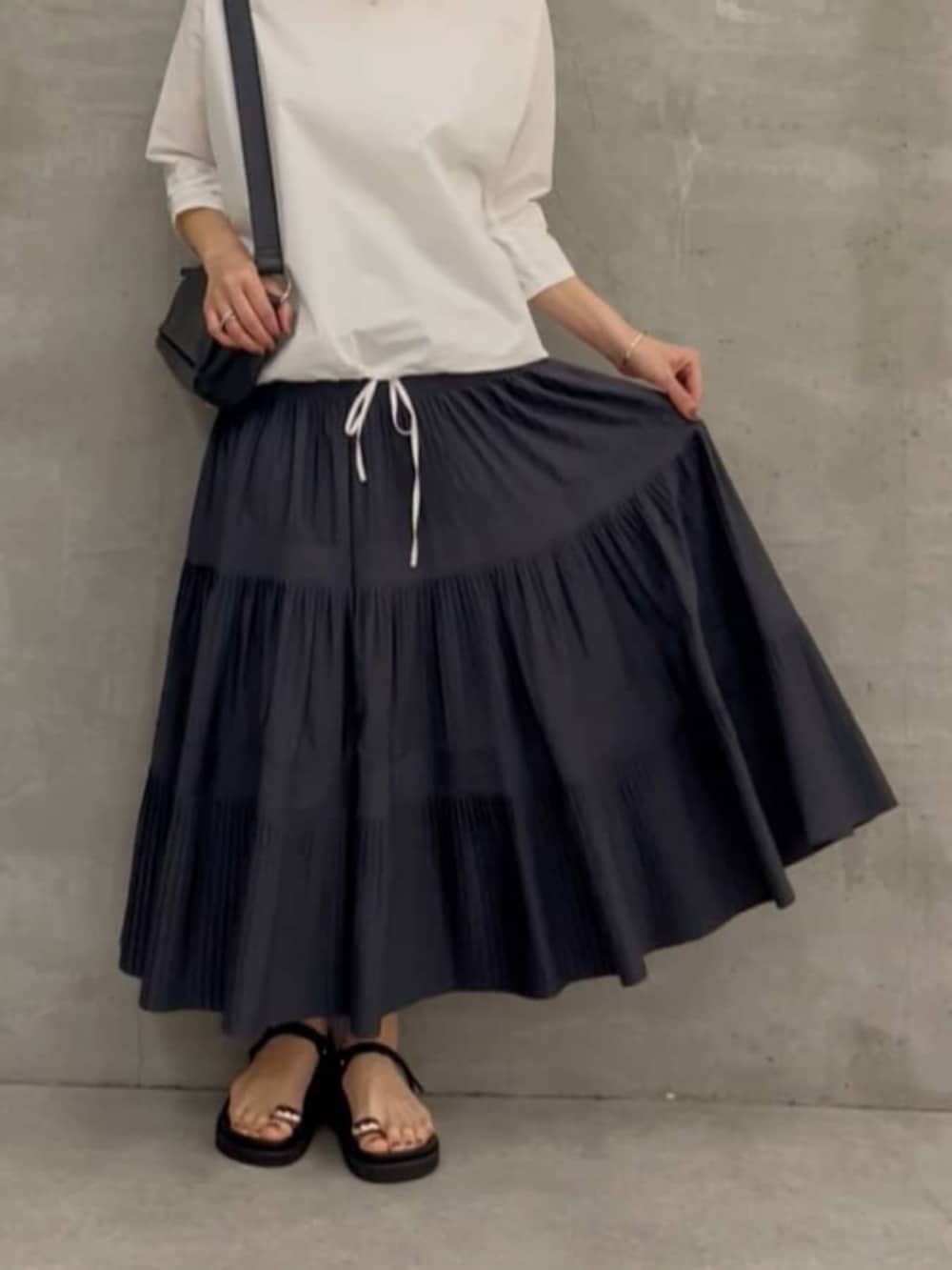 グレー系のスカート、ブラック系のショルダーバッグ、ホワイト系のシャツ/ブラウスを着用したレディースの春コーディネートの7枚目の写真