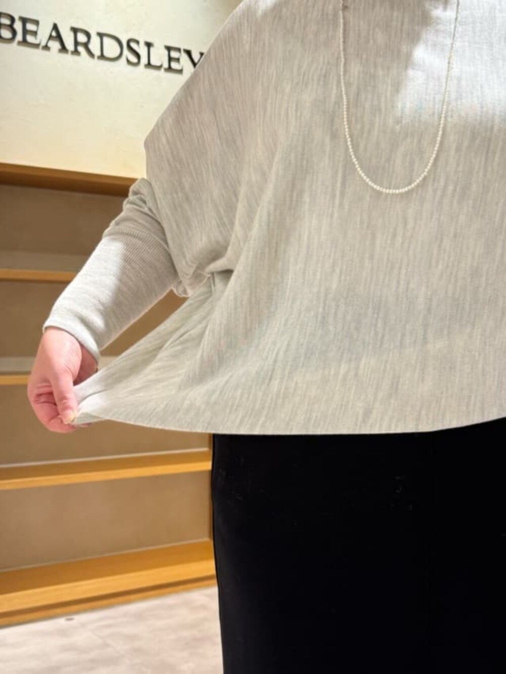 グリーン系のハンドバッグ、グレー系のニット/セーター、ブラック系のブーツを着用したレディースの冬コーディネートの8枚目の写真