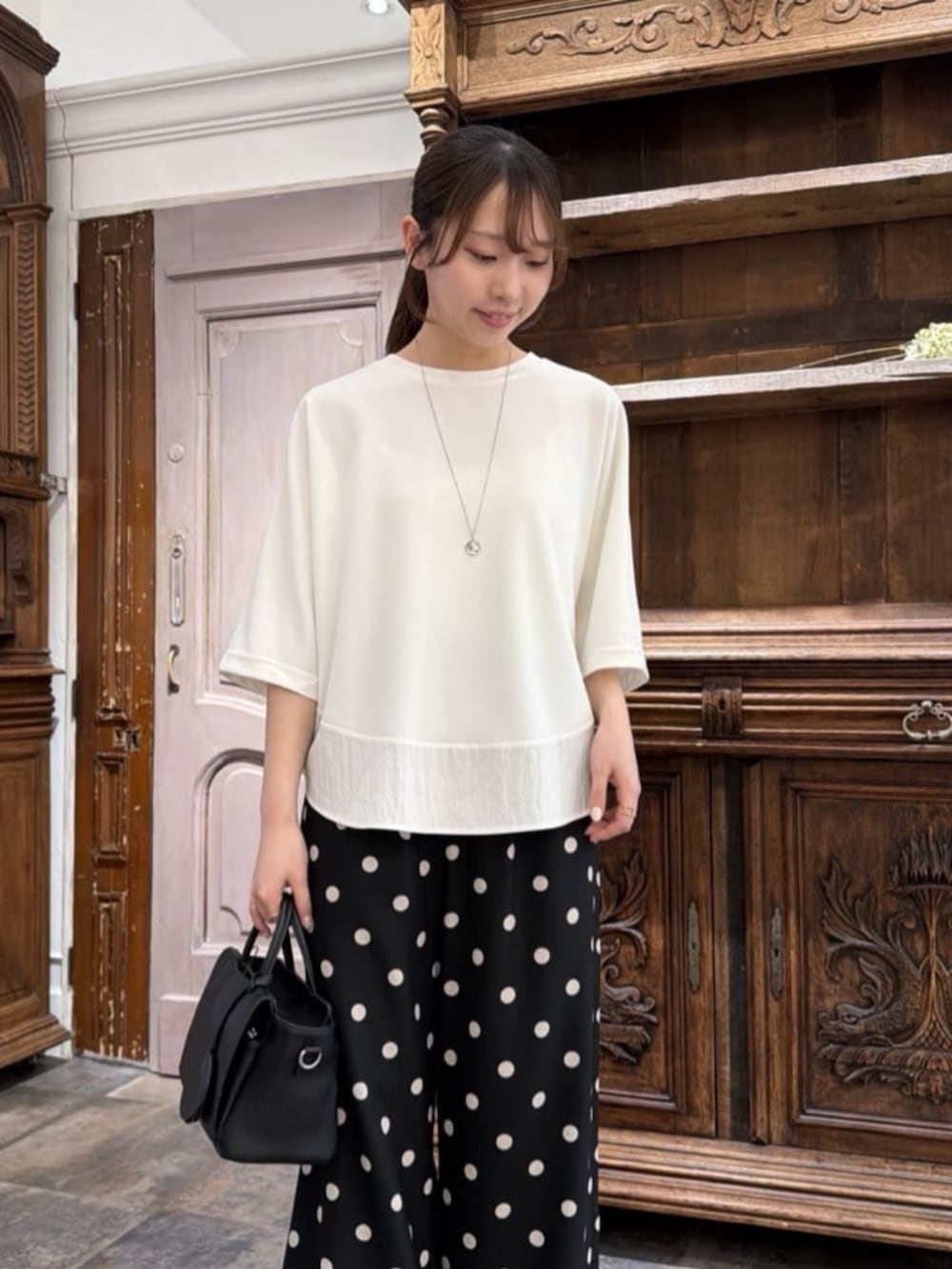 ブラック系のハンドバッグ、ブラック系のその他パンツ、ホワイト系のTシャツ/カットソーを着用したレディースの春コーディネートの4枚目の写真