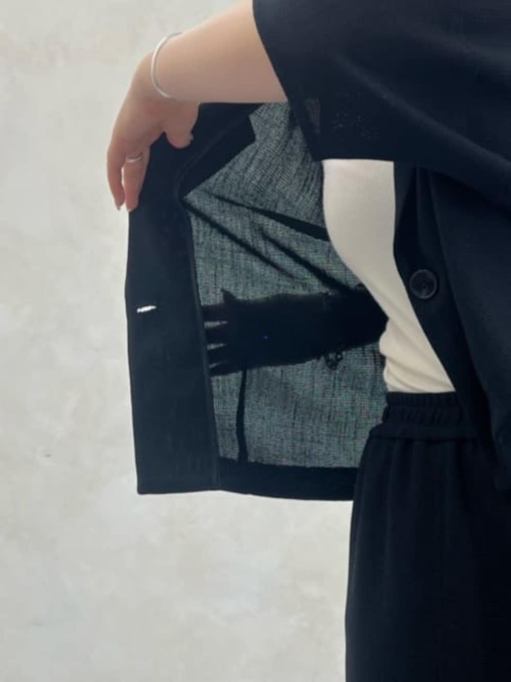 グレー系のハンドバッグ、ブラック系のテーラードジャケット、ブラック系のスカートを着用したレディースの春コーディネートの9枚目の写真