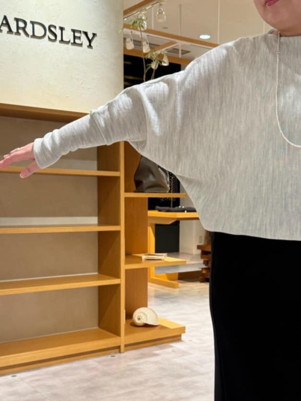 グリーン系のハンドバッグ、グレー系のニット/セーター、ブラック系のブーツを着用したレディースの冬コーディネートの7枚目の写真