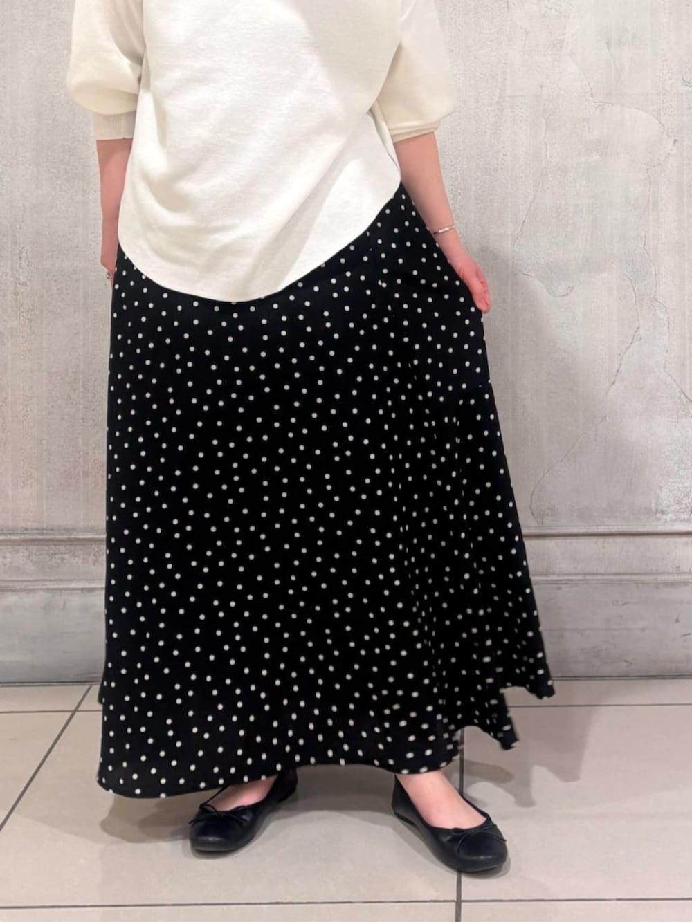 ブラック系のハンドバッグ、ブラック系のスカート、ホワイト系のTシャツ/カットソーを着用したレディースの春コーディネートの7枚目の写真