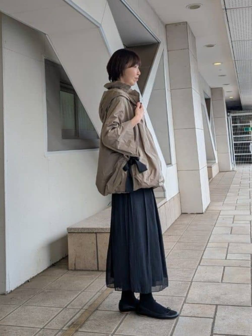 グリーン系のハンドバッグ、ブラック系のその他パンツ、ブラウン系のブルゾンを着用したレディースの冬コーディネートの2枚目の写真