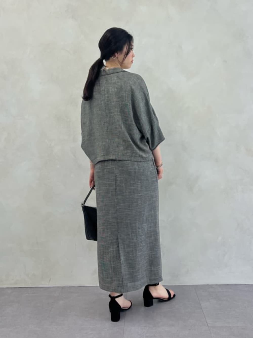 ブラック系のトートバッグ、ベージュ系のテーラードジャケット、ベージュ系のスカートを着用したレディースの春コーディネートの2枚目の写真