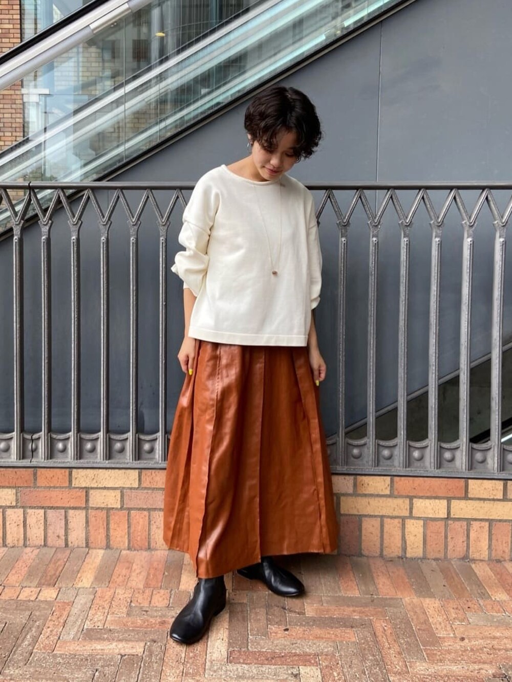 ホワイト系のニット/セーター、イエロー系のスカート、ブラック系のブーツを着用したレディースの秋コーディネートの2枚目の写真