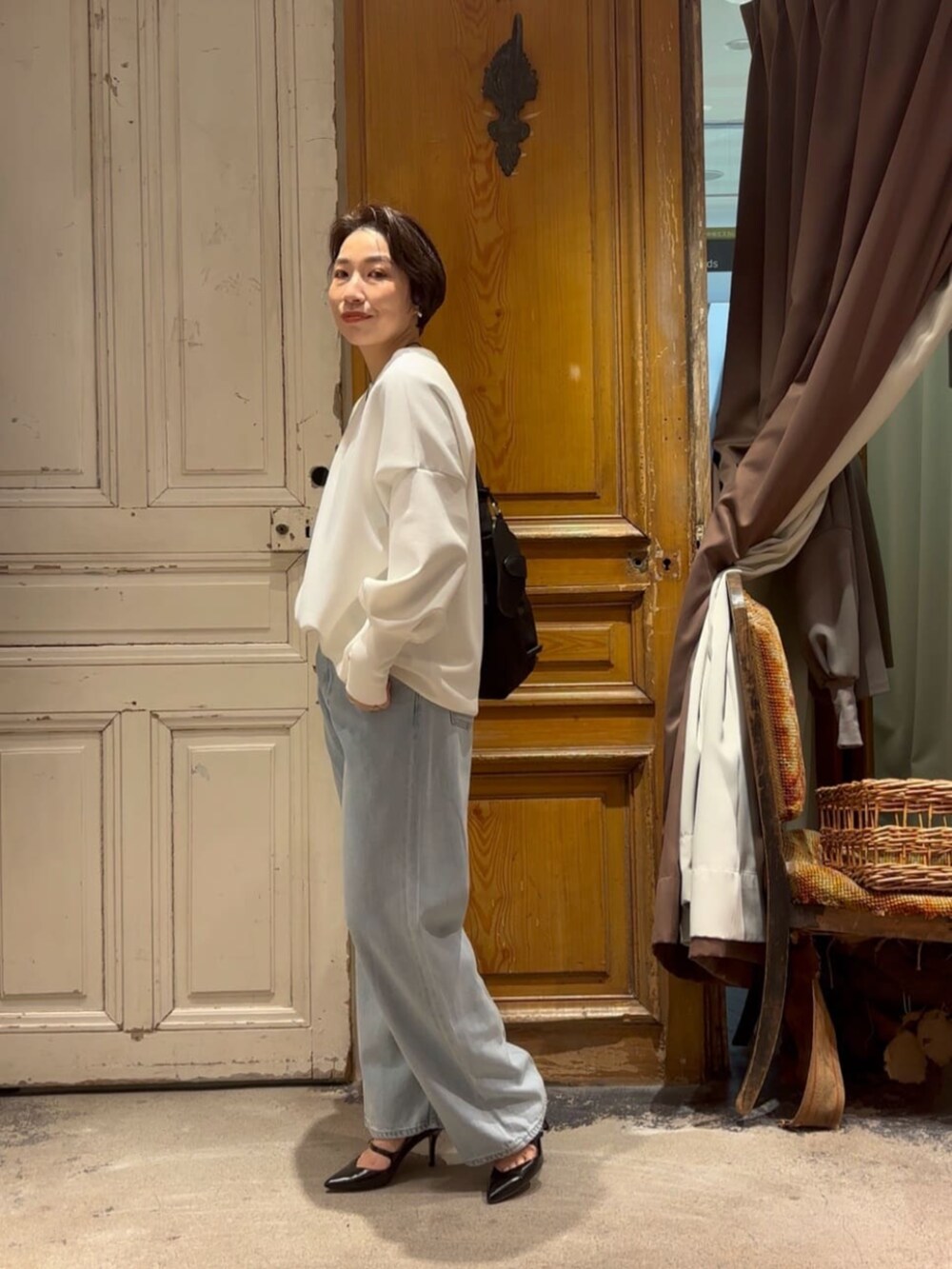 ブルー系のデニムパンツ、ホワイト系のTシャツ/カットソー、ブラック系のショルダーバッグを着用したレディースの冬コーディネートの4枚目の写真