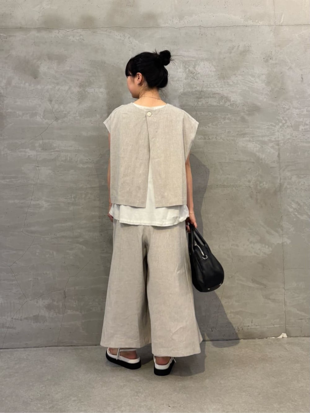 ブラック系のボストンバッグ、ホワイト系のサンダル、ホワイト系のシャツ/ブラウスを着用したレディースの春コーディネートの3枚目の写真