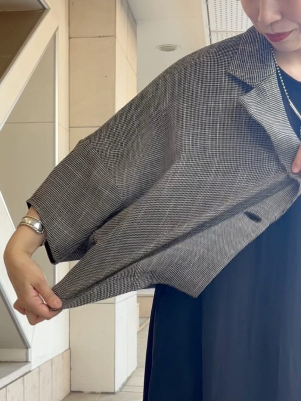 ベージュ系のテーラードジャケット、ブラック系のワンピース、ブラック系のスニーカーを着用したレディースの夏コーディネートの7枚目の写真