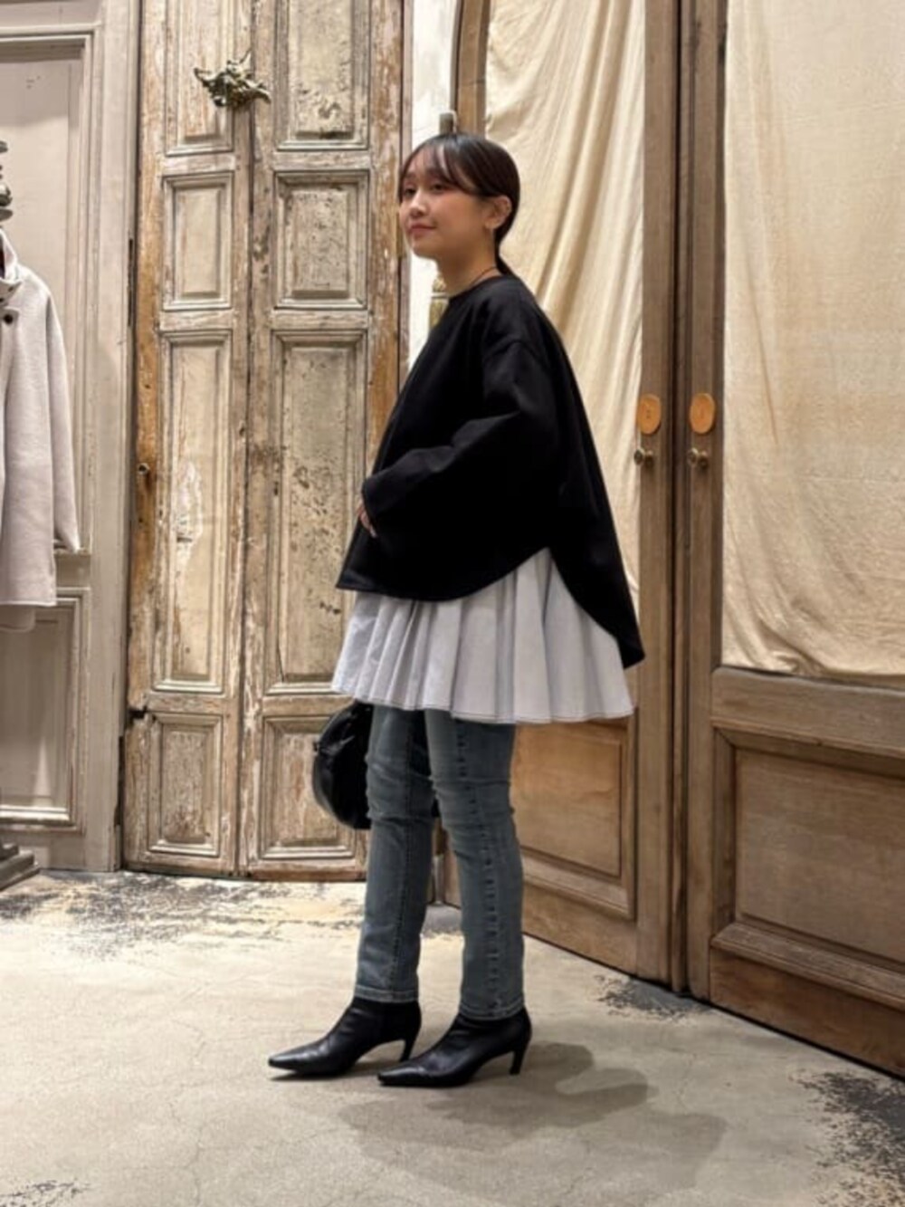 ブルー系のデニムパンツ、ブラック系のボストンバッグ、ブラック系のTシャツ/カットソーを着用したレディースの冬コーディネートの3枚目の写真