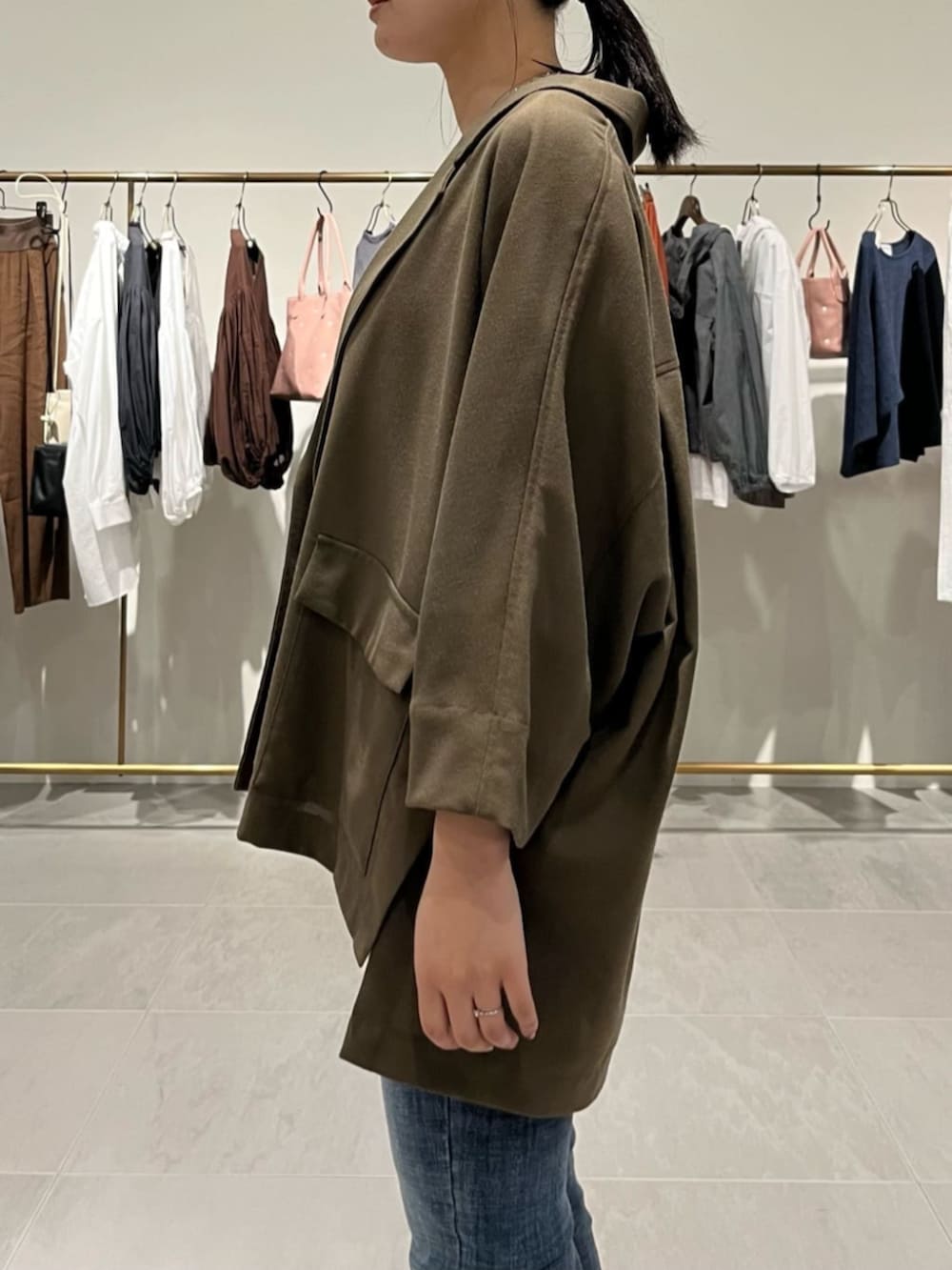 ブルー系のデニムパンツ、ブラック系のショルダーバッグ、ブラウン系のテーラードジャケットを着用したレディースの春コーディネートの6枚目の写真