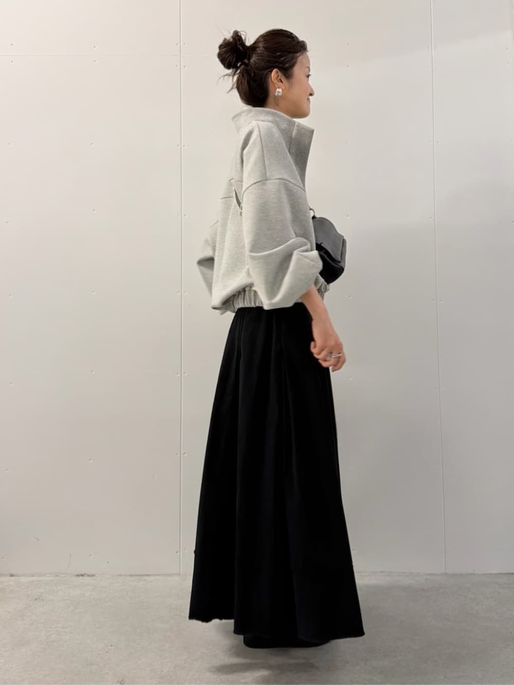 ブラック系のショルダーバッグ、ブラック系のスカート、グレー系のTシャツ/カットソーを着用したレディースの夏コーディネートの2枚目の写真