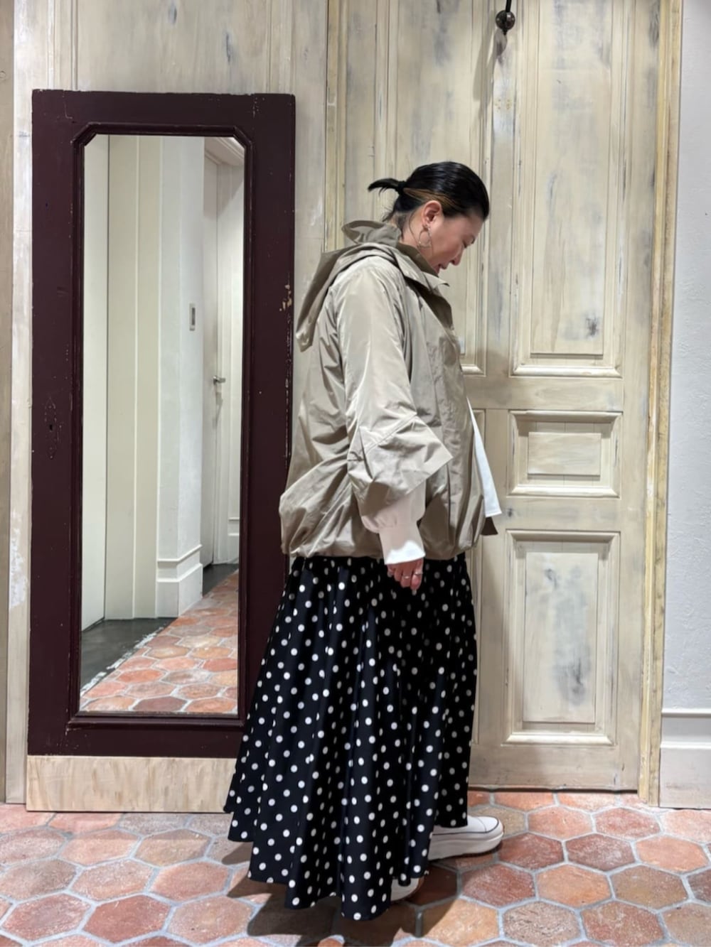 グリーン系のハンドバッグ、ブラック系のスカート、ブラウン系のブルゾンを着用したレディースの冬コーディネートの2枚目の写真