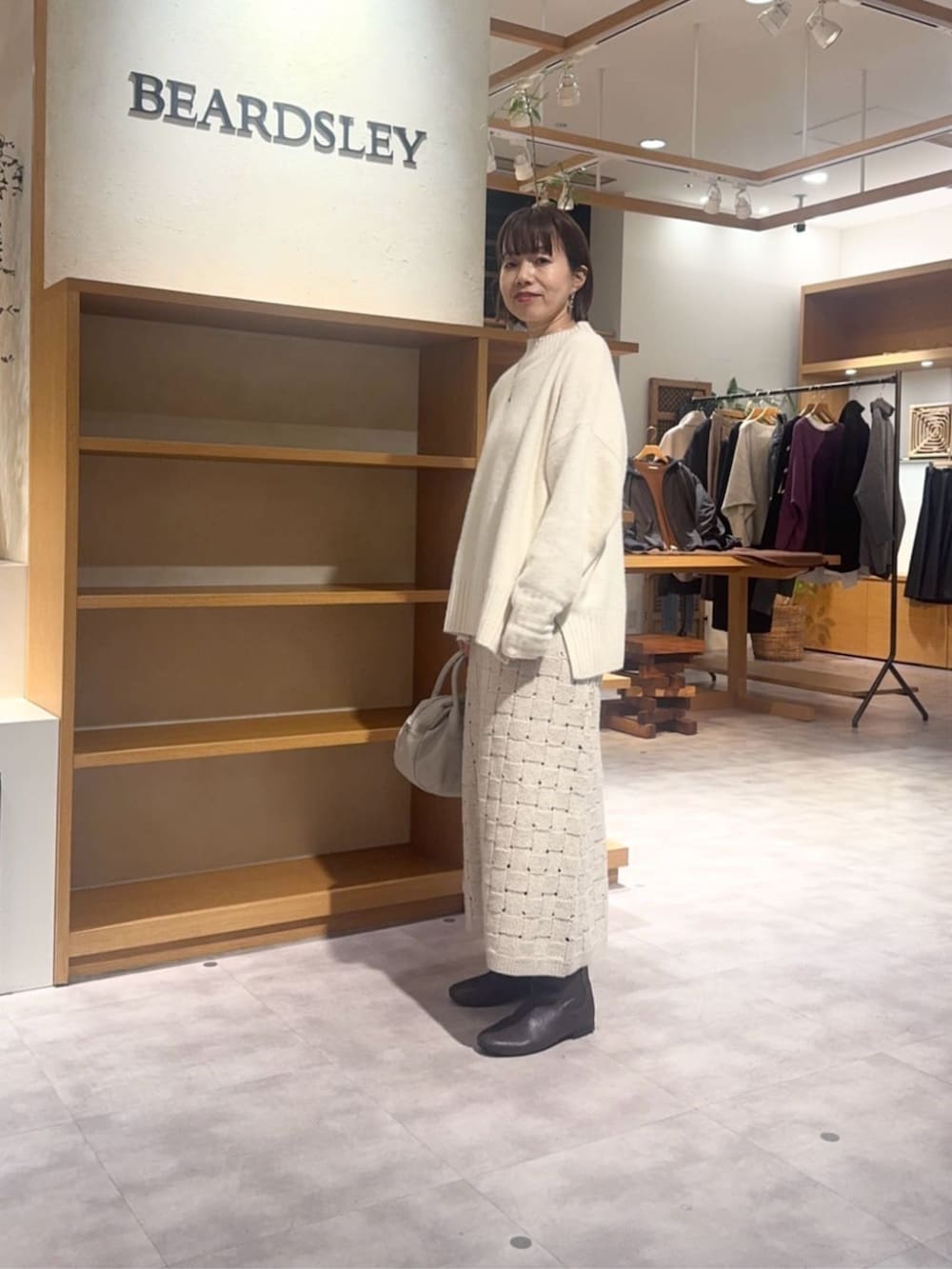 グレー系のボストンバッグ、ベージュ系のスカート、ブラウン系のダウンジャケット/コートを着用したレディースの冬コーディネートの7枚目の写真