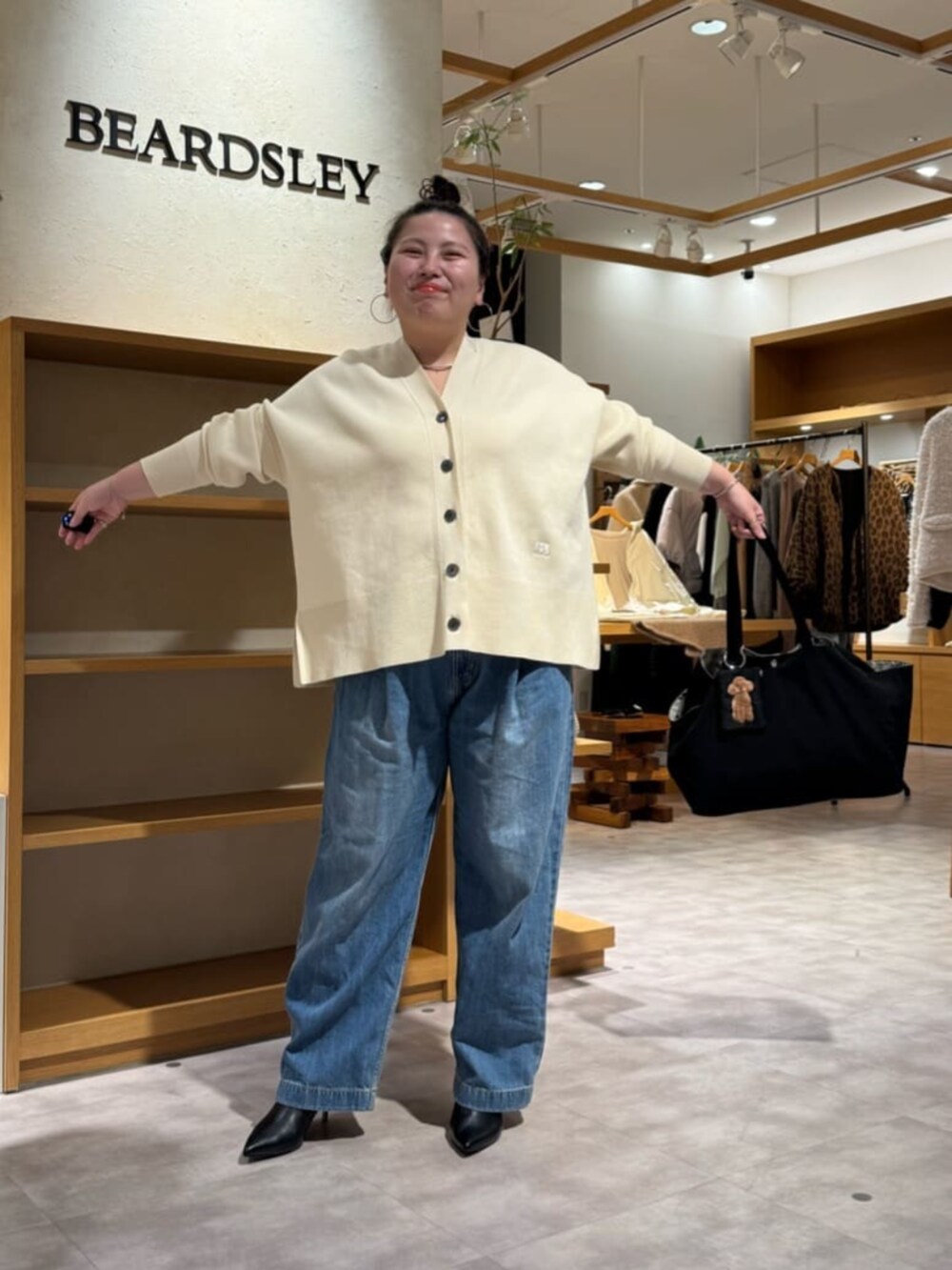 グレー系のボストンバッグ、ブラック系のブーツ、ホワイト系のカーディガン/ボレロを着用したレディースの冬コーディネートの3枚目の写真