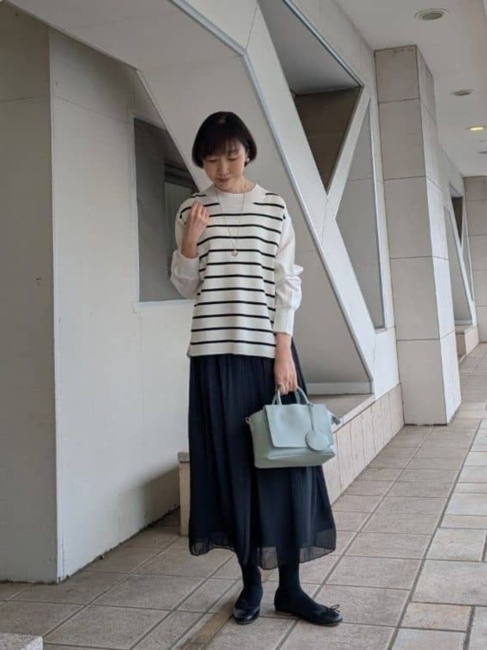 グリーン系のハンドバッグ、ブラック系のその他パンツ、ブラウン系のブルゾンを着用したレディースの冬コーディネートの5枚目の写真