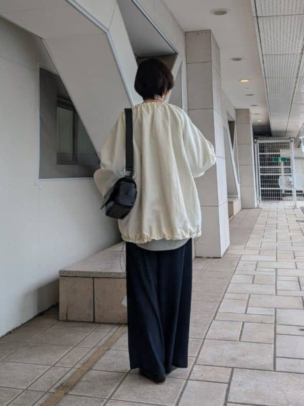 ブルー系のその他パンツ、グレー系のニット/セーター、ホワイト系のノーカラージャケットを着用したレディースの冬コーディネートの3枚目の写真