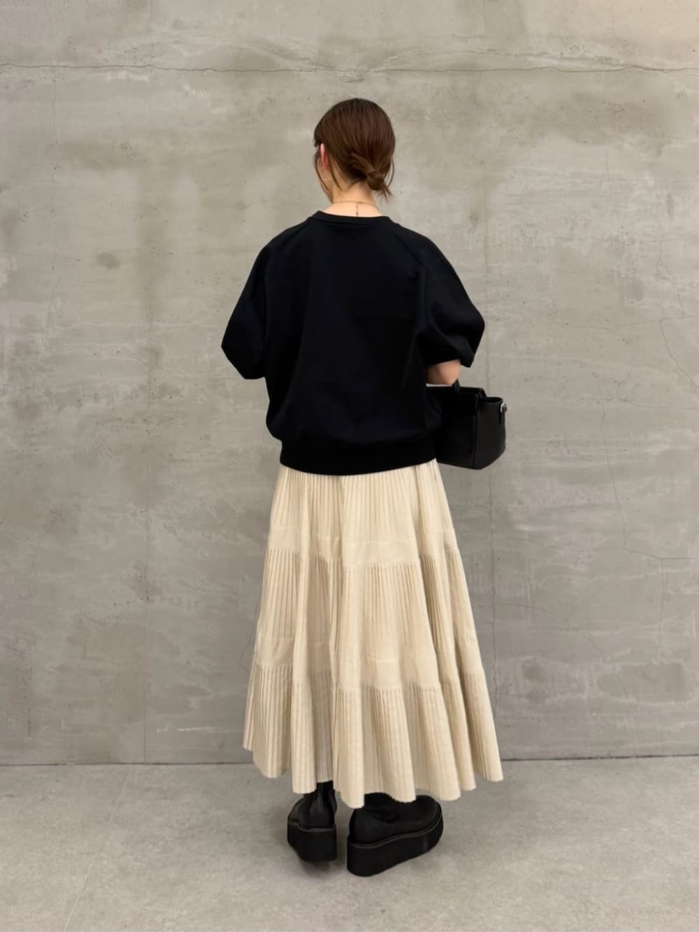 ホワイト系のスカート、ブラック系のハンドバッグ、ブラック系のTシャツ/カットソーを着用したレディースの冬コーディネートの3枚目の写真