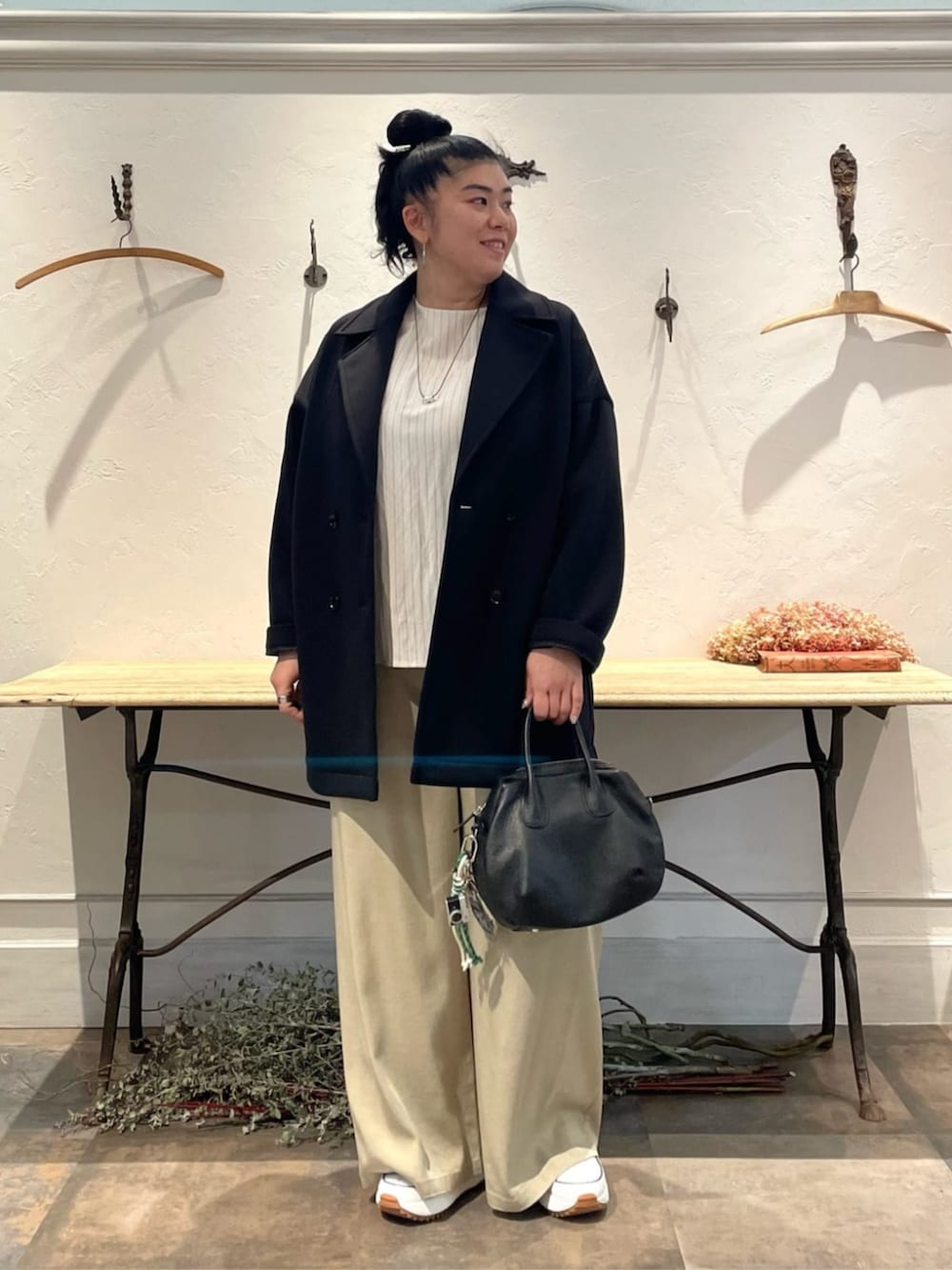 ブラック系のボストンバッグ、ベージュ系のその他パンツ、ブラック系のピーコートを着用したレディースの冬コーディネートの2枚目の写真