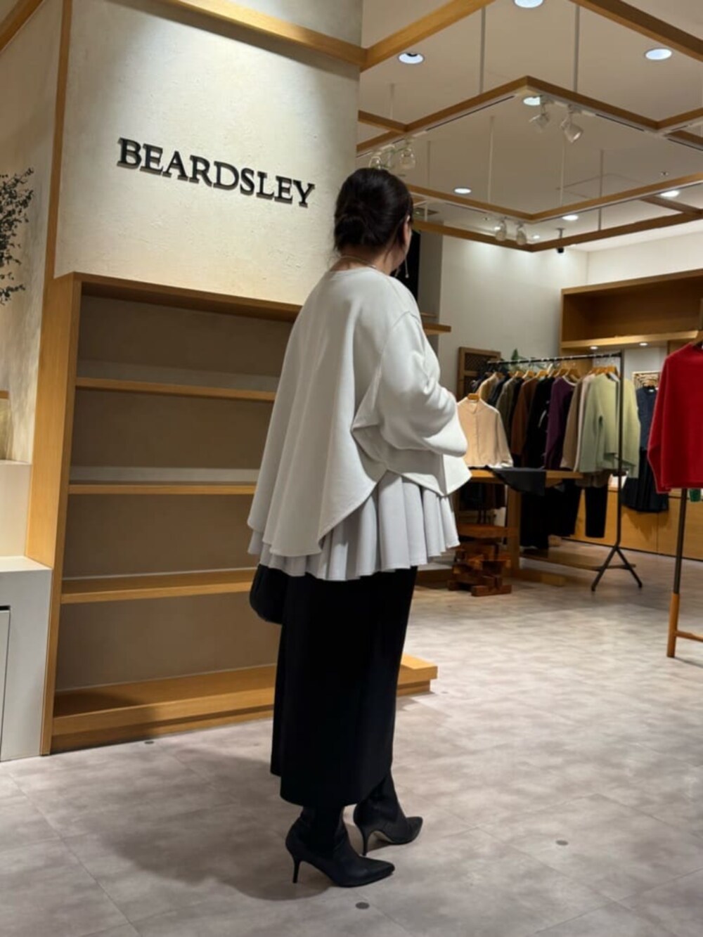 ブラック系のブーツ、ブラック系のスカート、ホワイト系のTシャツ/カットソーを着用したレディースの冬コーディネートの8枚目の写真