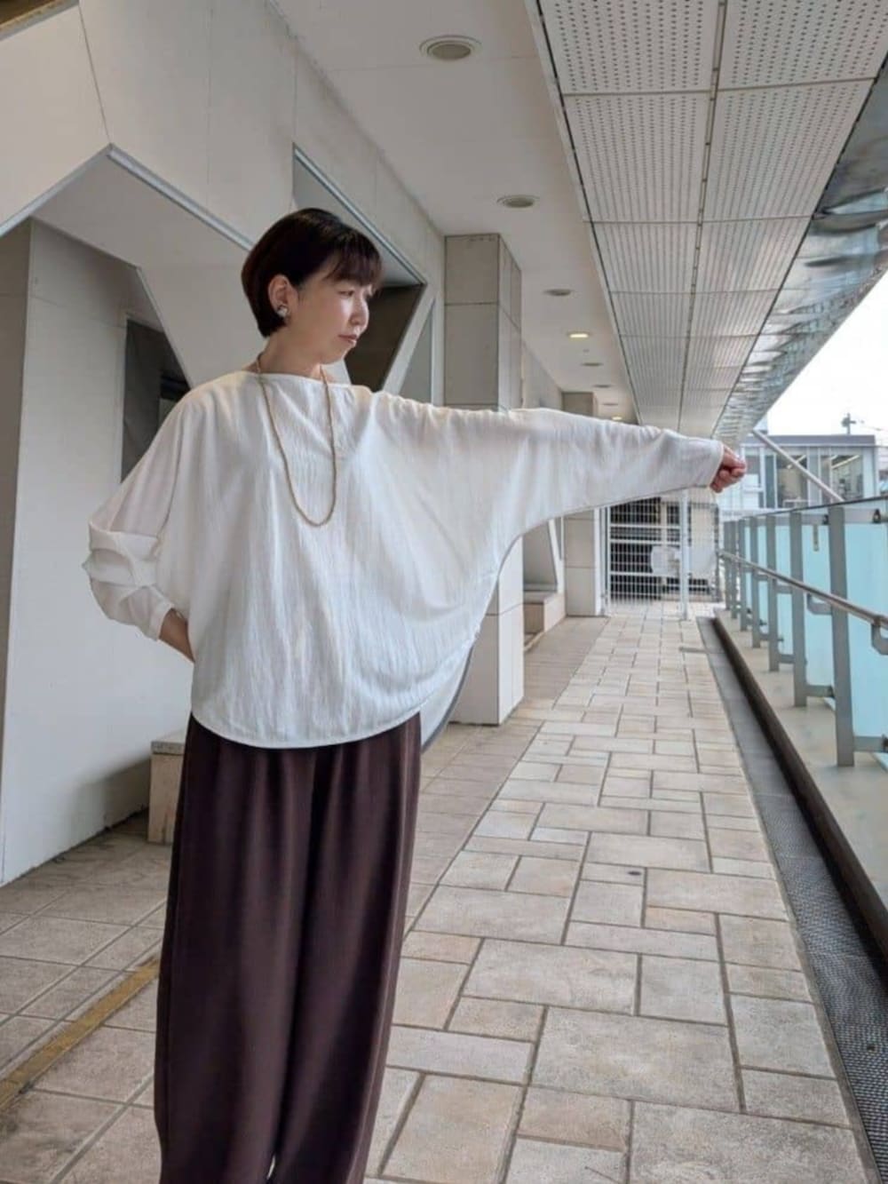 グレー系のハンドバッグ、ホワイト系のTシャツ/カットソー、ブラウン系のその他パンツを着用したレディースの夏コーディネートの5枚目の写真