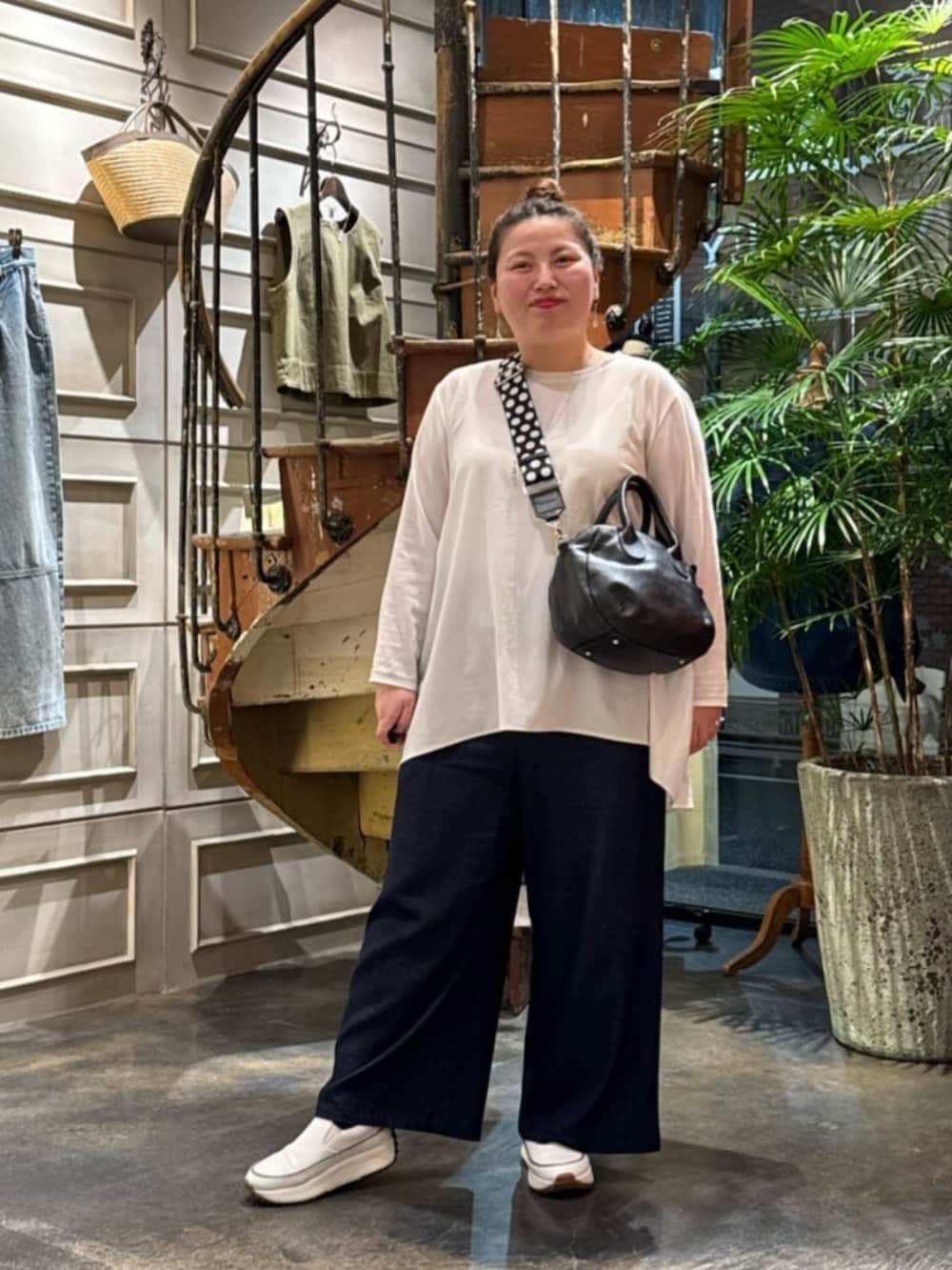 ホワイト系のTシャツ/カットソー、ブラック系のボストンバッグ、ホワイト系のスニーカーを着用したレディースの春コーディネートの2枚目の写真