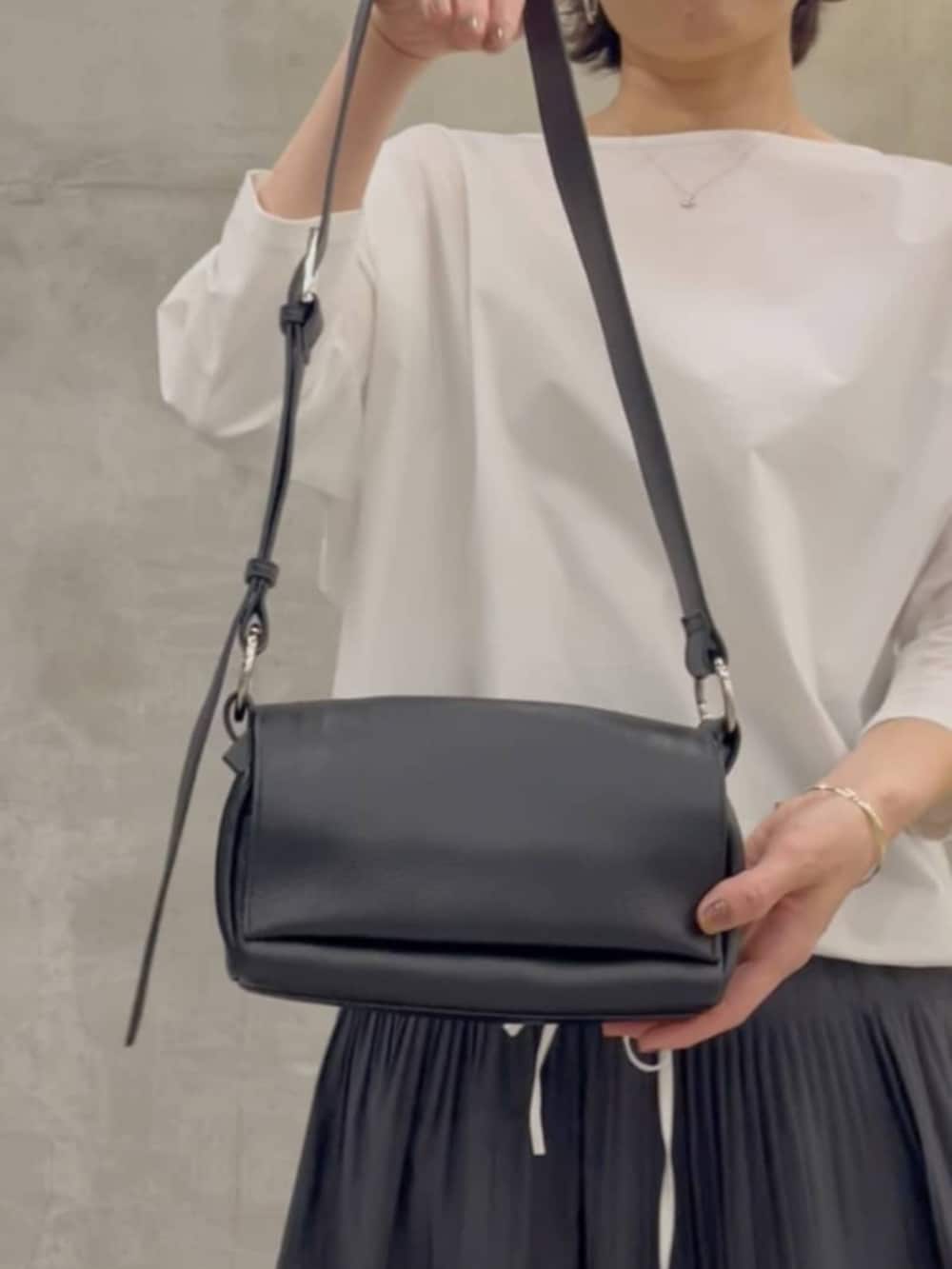 グレー系のスカート、ブラック系のショルダーバッグ、ホワイト系のシャツ/ブラウスを着用したレディースの春コーディネートの10枚目の写真