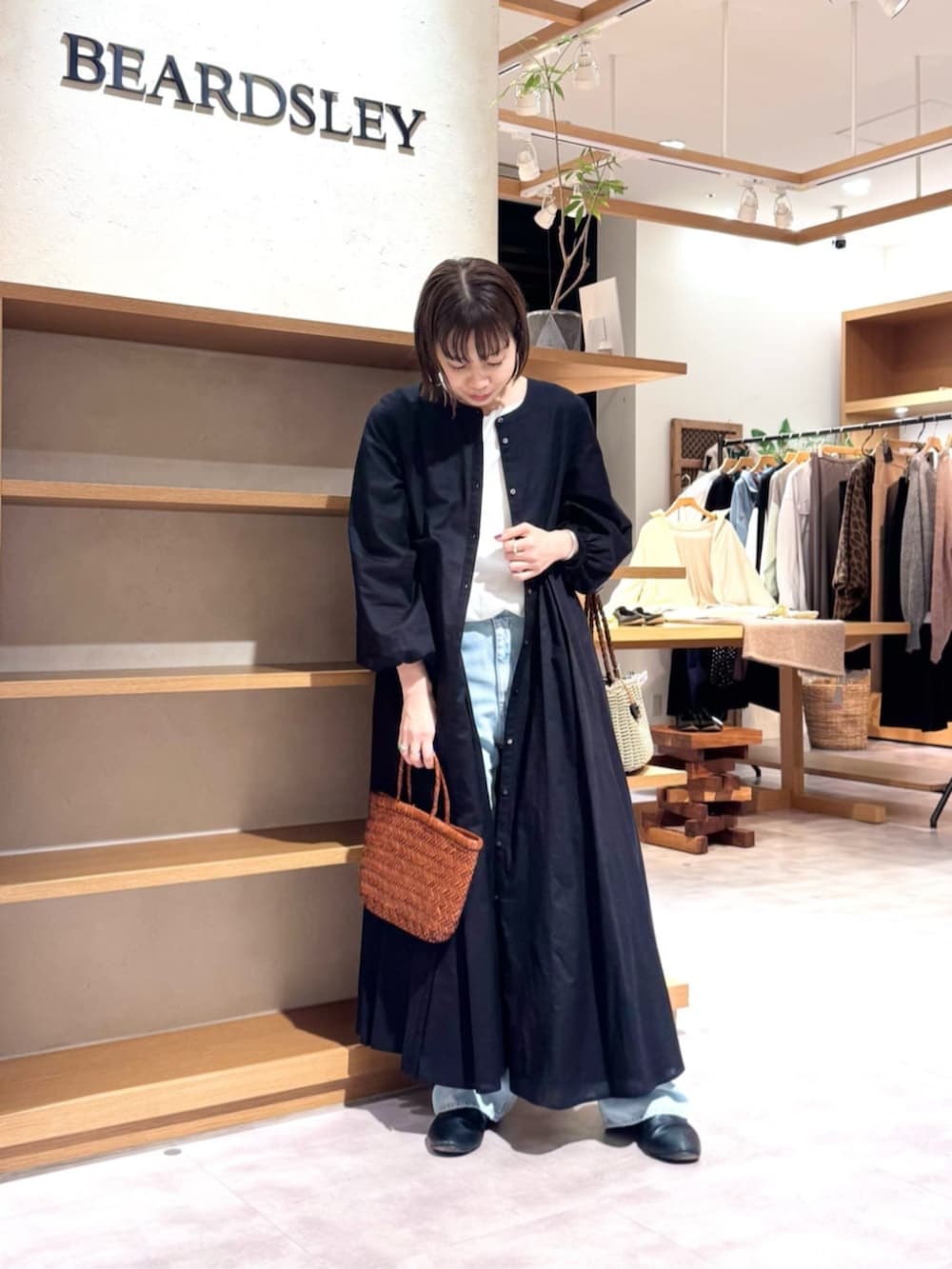 ブルー系のデニムパンツ、イエロー系のトートバッグ、ブラック系のワンピースを着用したレディースの冬コーディネートの2枚目の写真