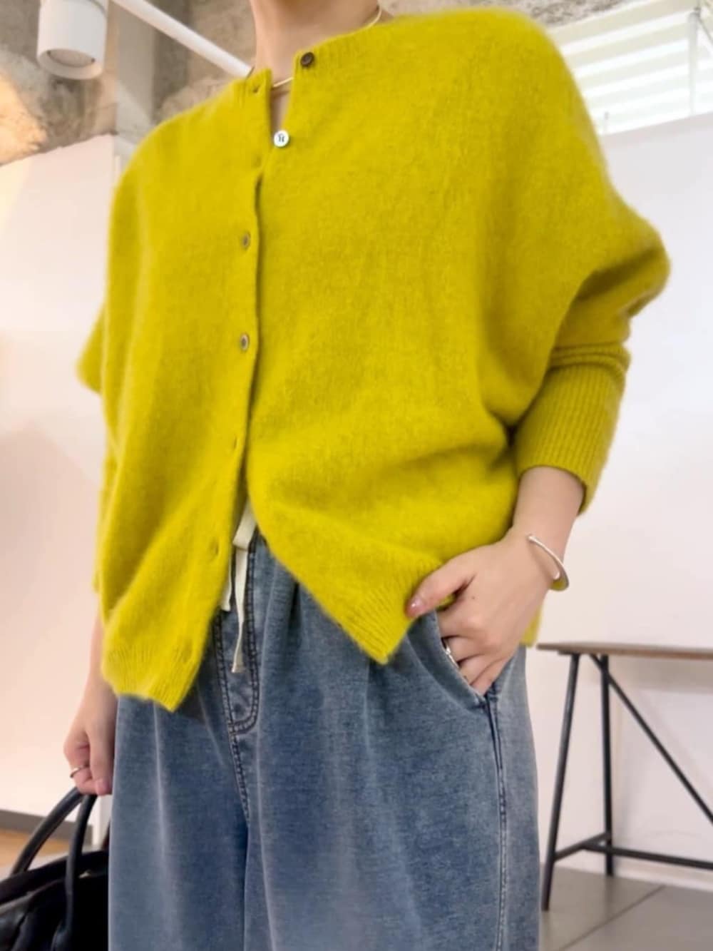ブラック系のトートバッグ、イエロー系のニット/セーター、ブルー系のその他パンツを着用したレディースの秋コーディネートの3枚目の写真