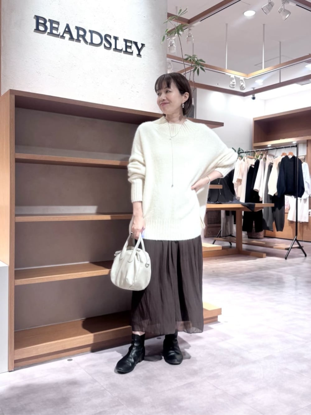 グレー系のボストンバッグ、ホワイト系のニット/セーター、ブラウン系のその他パンツを着用したレディースの冬コーディネートの3枚目の写真