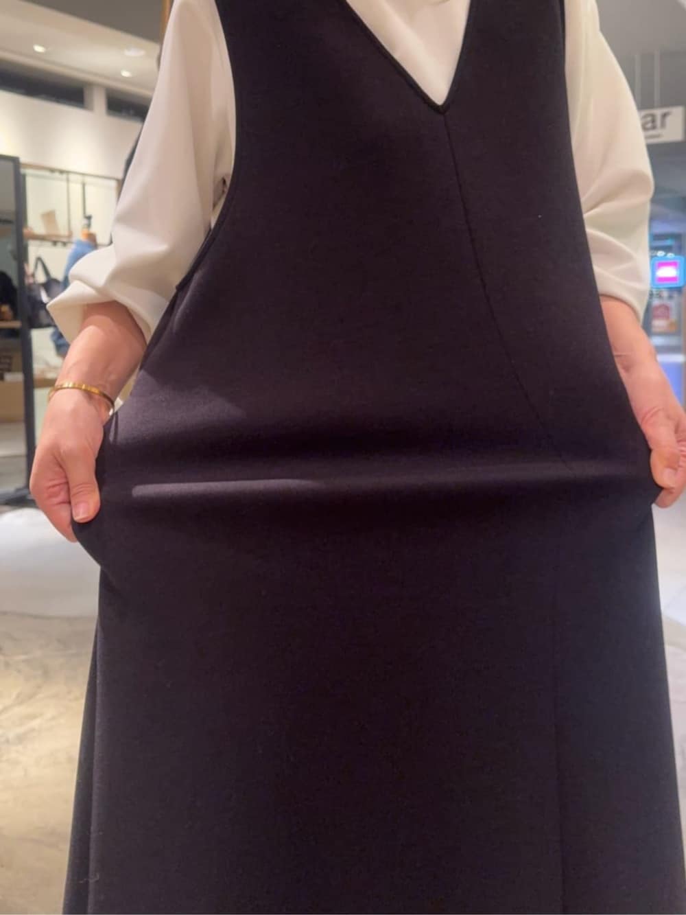 ホワイト系のシャツ/ブラウス、ブラック系のブーツ、ブラック系のジャンパースカートを着用したレディースの冬コーディネートの4枚目の写真