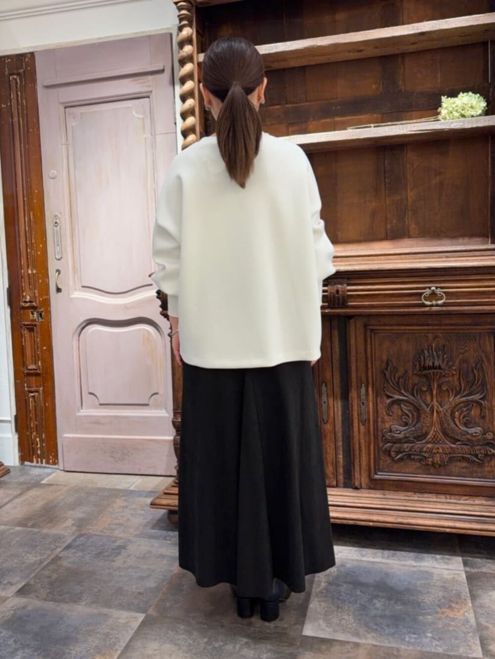 ブラック系のスカート、ブラック系のショルダーバッグ、ホワイト系のTシャツ/カットソーを着用したレディースの冬コーディネートの2枚目の写真